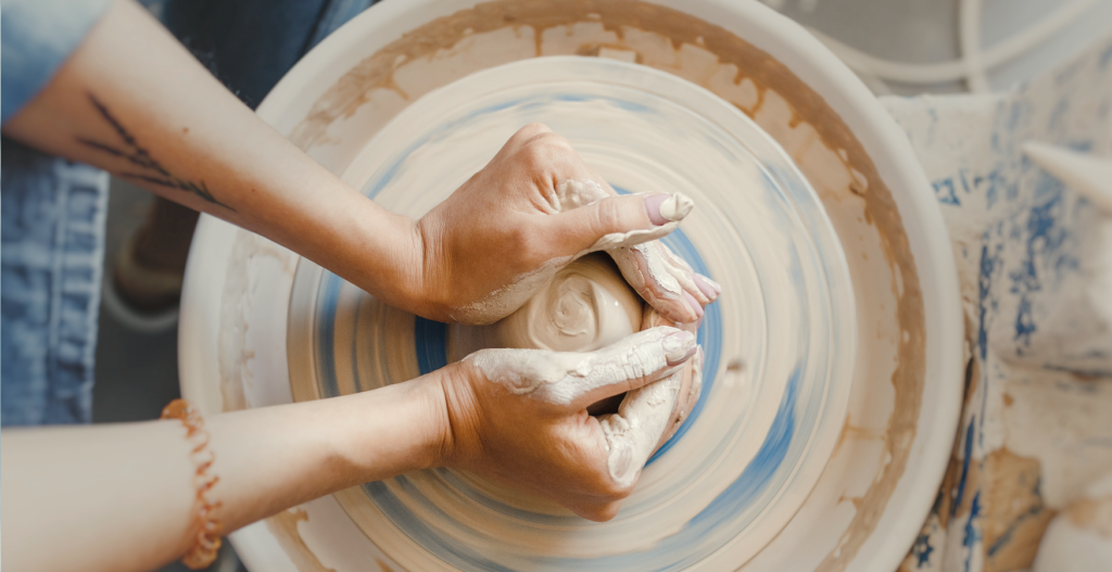 A woman's hands shaping clay on a pottery wheel